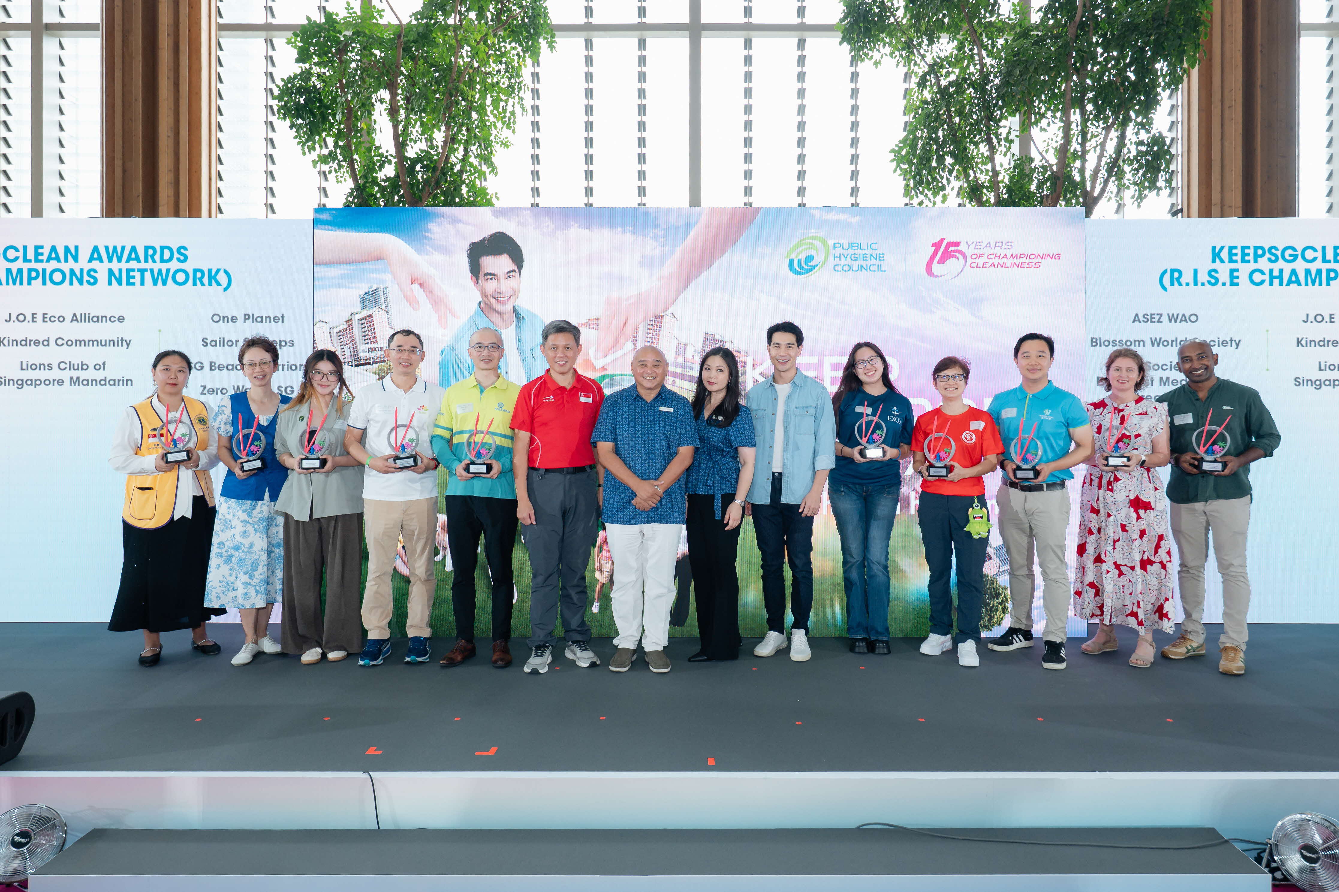 Award recipients of the KeepSGClean Awards (R.I.S.E Champions Network) posing on stage with their trophies at the Keep Singapore Clean 2026 campaign launch, with the Public Hygiene Council backdrop and a list of award recipients displayed behind them.